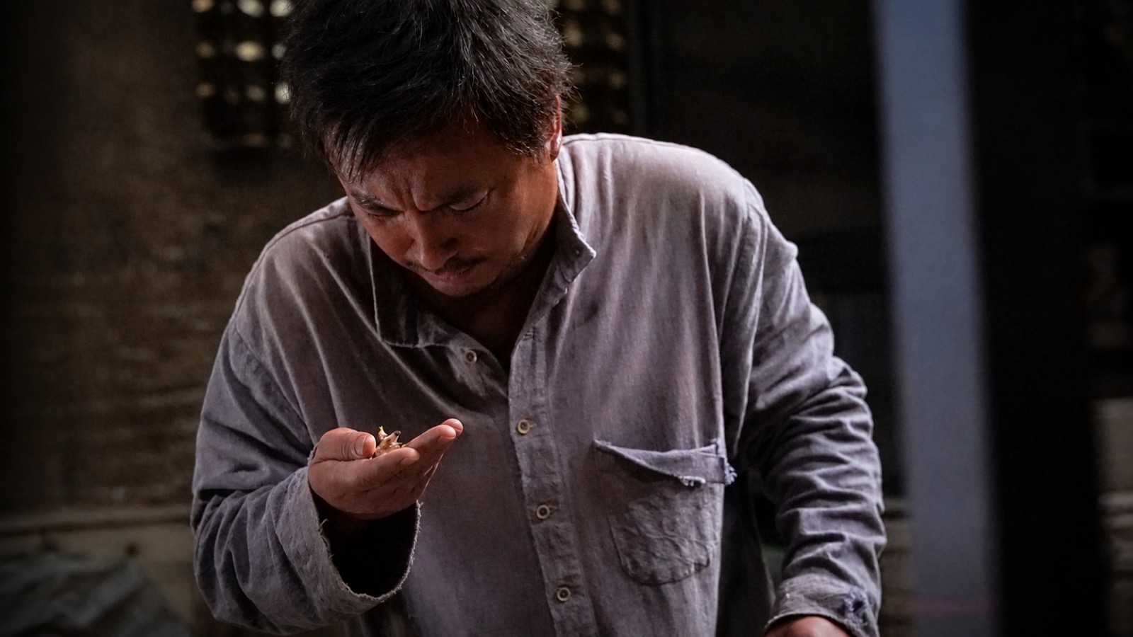 Xu Fu looks down at his palms; what the war left behind has no lines of dialogue